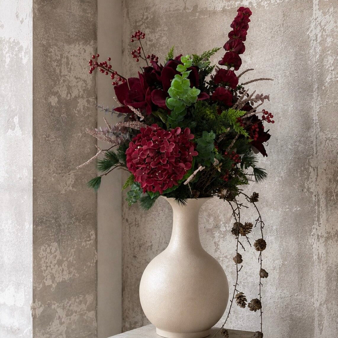 Bordeaux Irlands klokker i en blandet buket med hortensia, bær og grønne grene i en lys vase