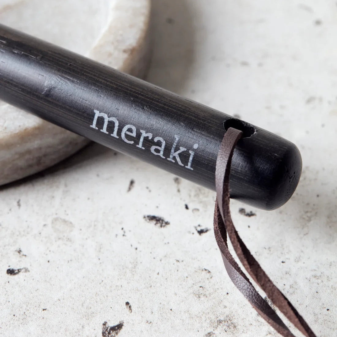 Nærbillede af bambusskaft med Meraki-logo og lædersnor